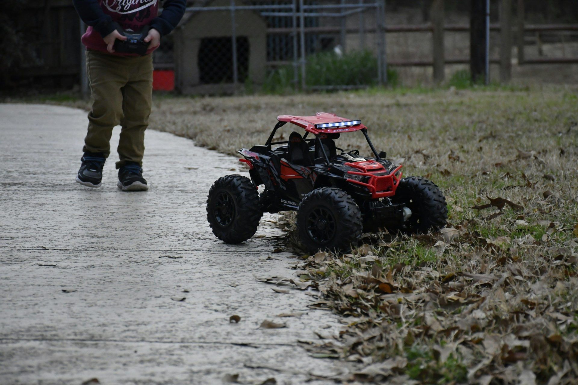 boy controlling red and black R/C UTV toy