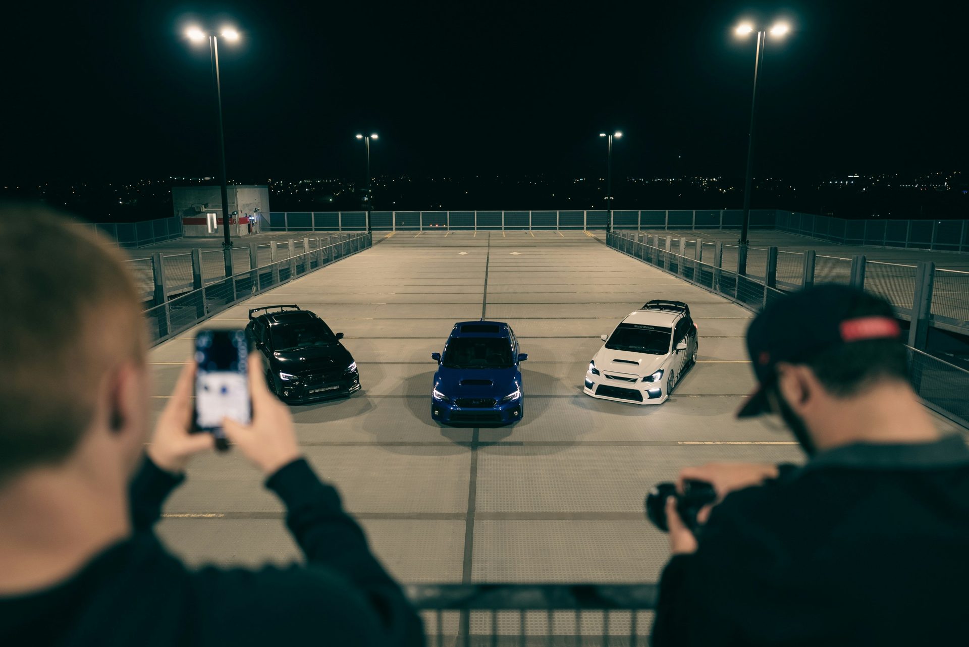 a man taking a picture of three cars in a parking lot